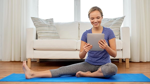 Experience our video library, woman looking at her tablet stretching